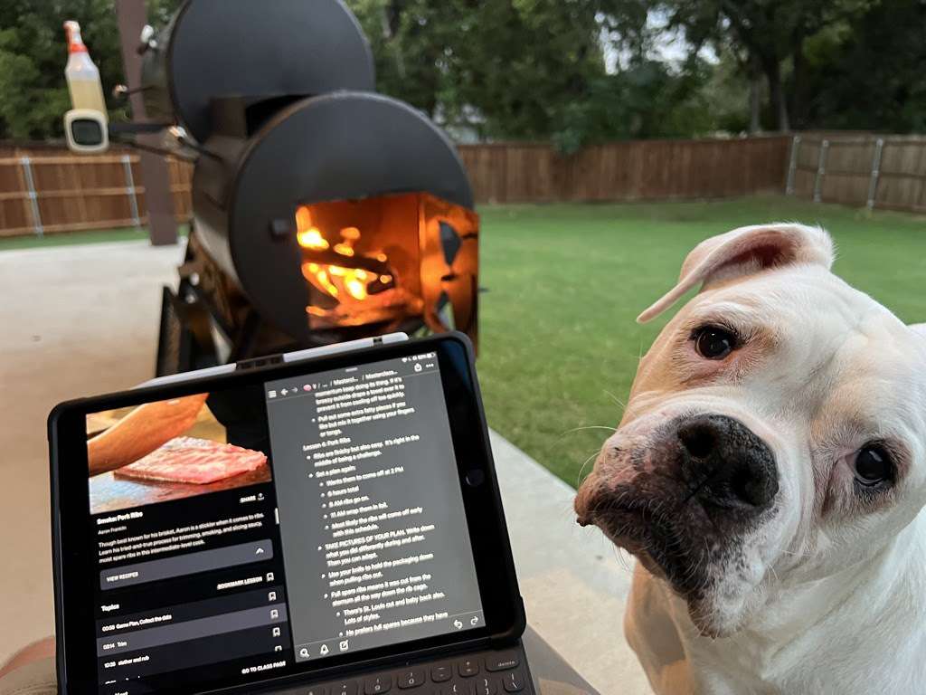 Offset smoker lit up and dog supervising