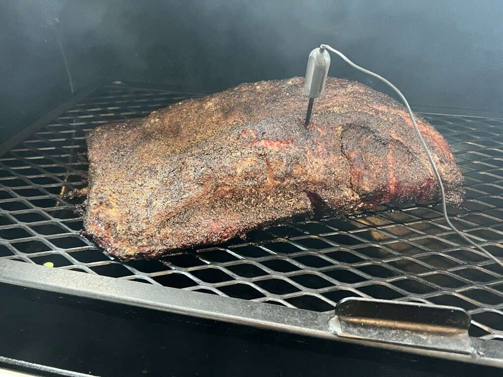 Half cooked beef brisket on smoker with probe